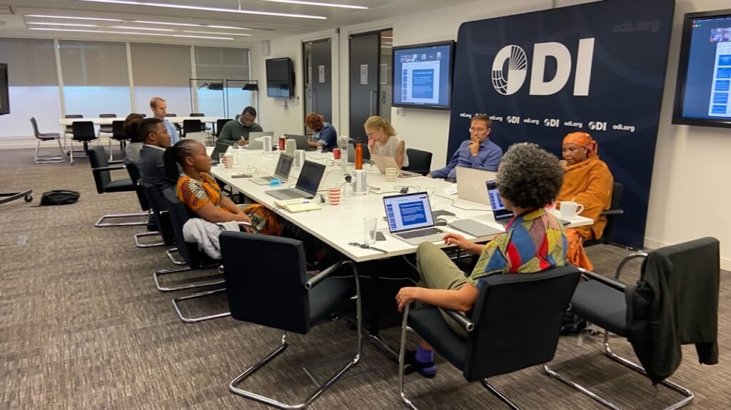 A group of researchers sit around a table in a boardroom with the ODI logo on the wall